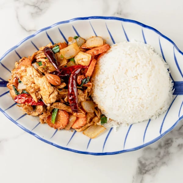 Spicy Thai chicken stir-fry with vegetables, almonds, and dried chilies, served with white rice.