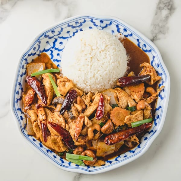 Thai cashew chicken with dried chilies, carrots, and scallions, served with white rice.
